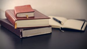 books forecasting Concentration selective focus photography of three books beside opened notebook