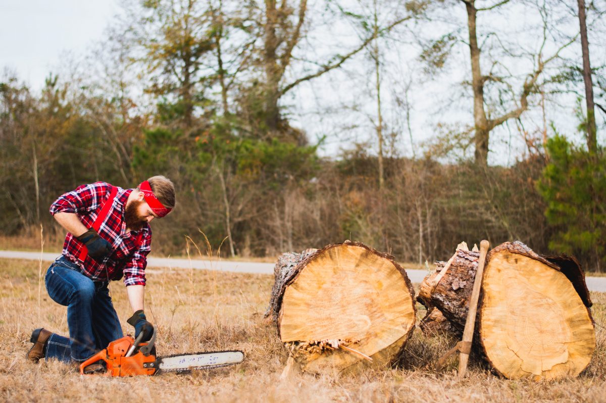 person using chainsaw in front of tree log