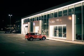 red car parked in front of white building during night time