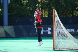First Sport Outdoor Sports New Hobby Field Hockey person jumping wearing red and white head gear in front of net goal