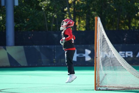 Outdoor Sports New Hobby Field Hockey person jumping wearing red and white head gear in front of net goal