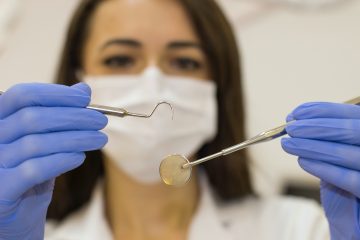 Dental Implants dentist woman in white shirt holding blue plastic spoon