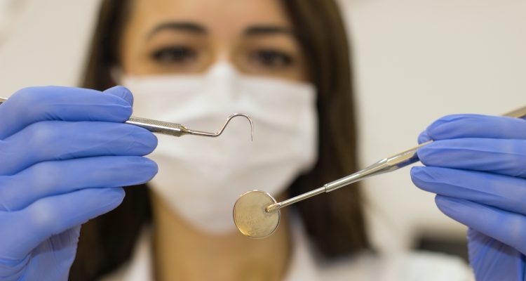 Dental Implants dentist woman in white shirt holding blue plastic spoon