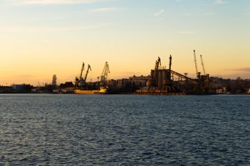 Dredging silhouette of buildings near body of water during sunset