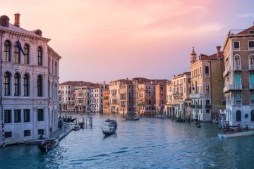 italy photo of gondolas on body of water between buildings