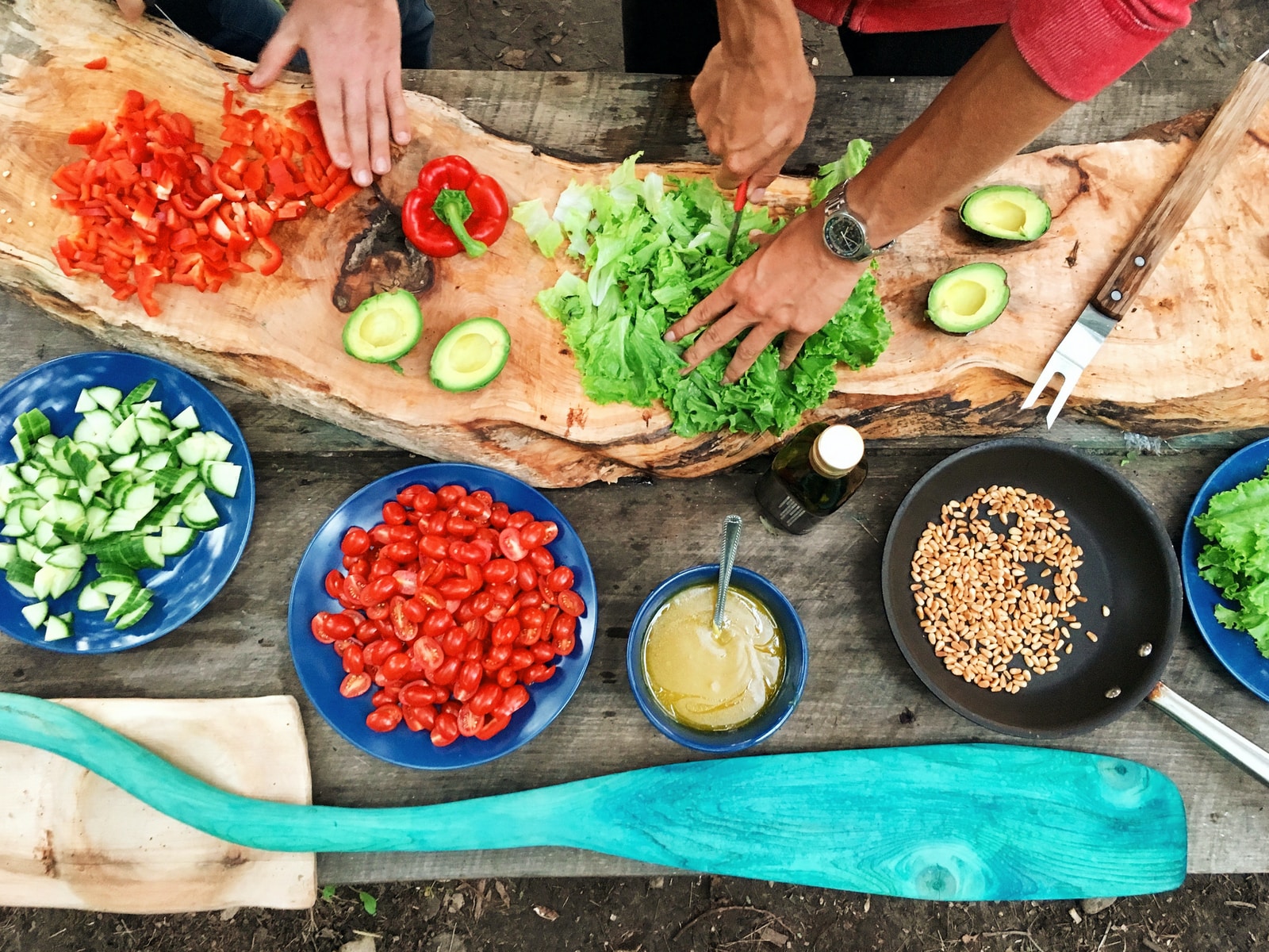 cooking Food Groups Eating Habits Outdoor Kitchen person slicing green vegetable in front of round ceramic plates with assorted sliced vegetables during daytime
