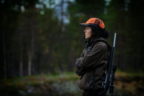 Aspiring Hunter woman carrying hunting rifle in woods