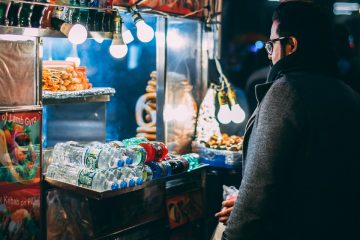 Food Cart man with coat standing in front of food cart during nighttime