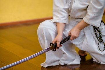 katana man holding black and gray katana