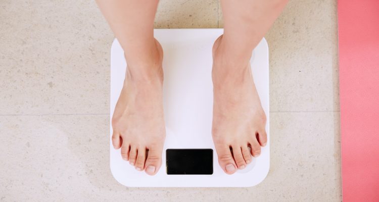 in Shape person standing on white digital bathroom scale