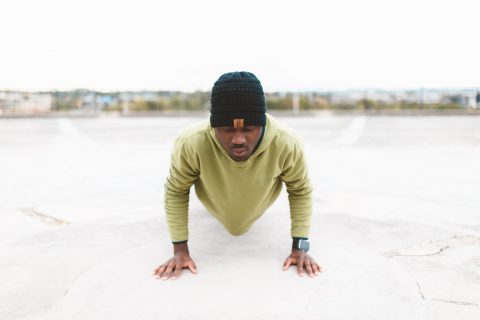 Low Testosterone Home Workout man in green long-sleeved shirt doing a push-up on gray concrete pavement