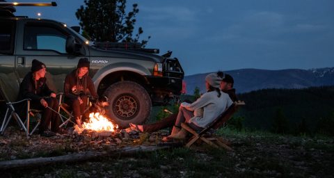 Overlanding 4x4 Off-Road Truck man in white shirt sitting on brown wooden chair near black suv during night time
