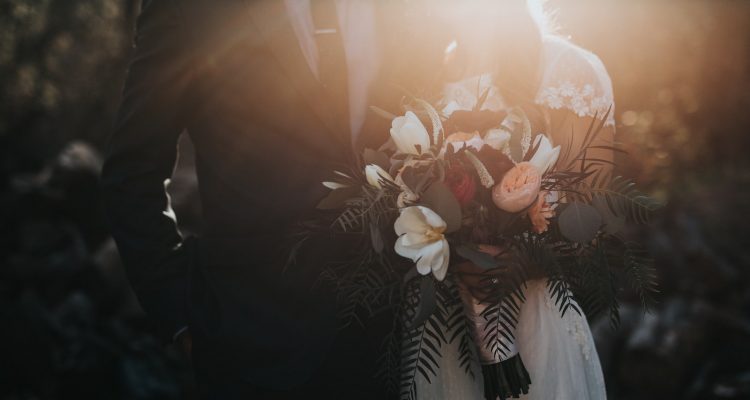 Wedding groom beside bride holding bouquet flowers