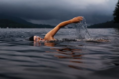 swimmer man swimming on body of water