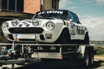 transporting a vehicle white and black coupe on trailer during daytime