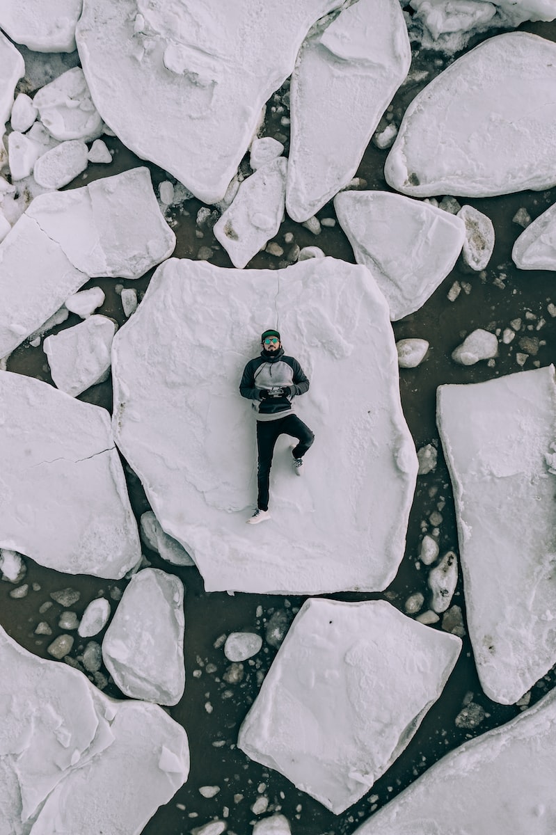 stressful travel adventure back pain Antarctica man lying on iceberg during daytime