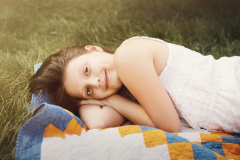 Quilts girl lies on textile on grass
