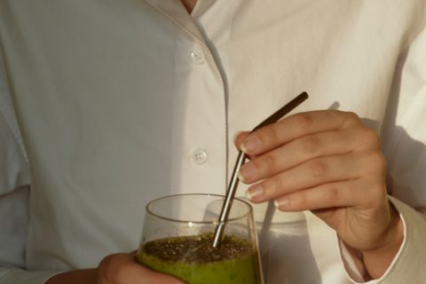 Kratom person in white button up shirt holding clear drinking glass with green liquid