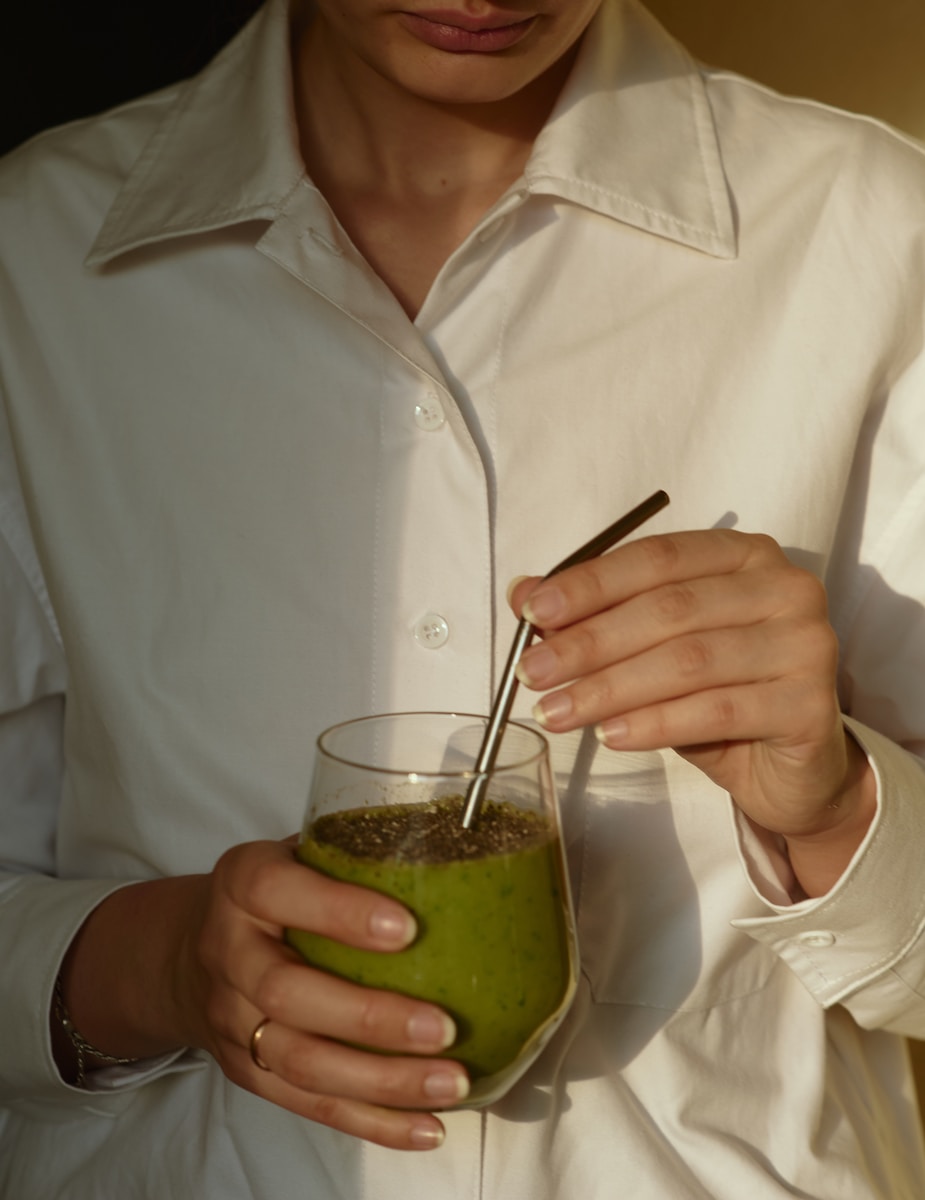 relaxation Kratom person in white button up shirt holding clear drinking glass with green liquid