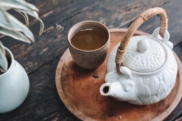 Tea white and brown ceramic teapot on wooden tray