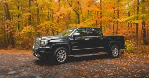 fuel best diesel truck black GMC crew cab pickup truck parked near brown trees during daytime