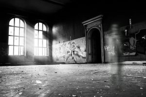 haunted grayscale photo of person standing inside building