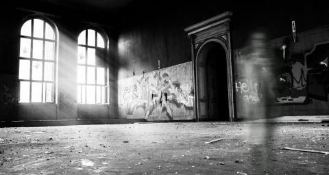 haunted grayscale photo of person standing inside building