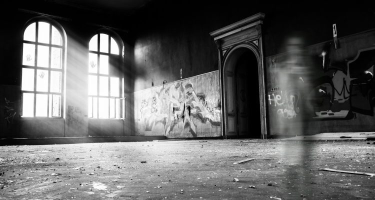 haunted grayscale photo of person standing inside building