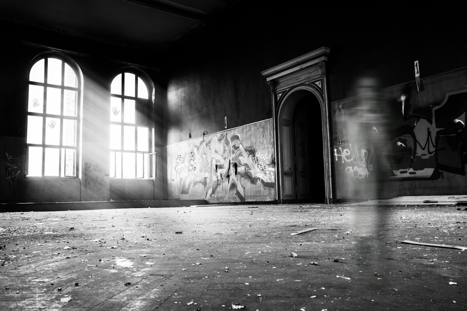 haunted grayscale photo of person standing inside building