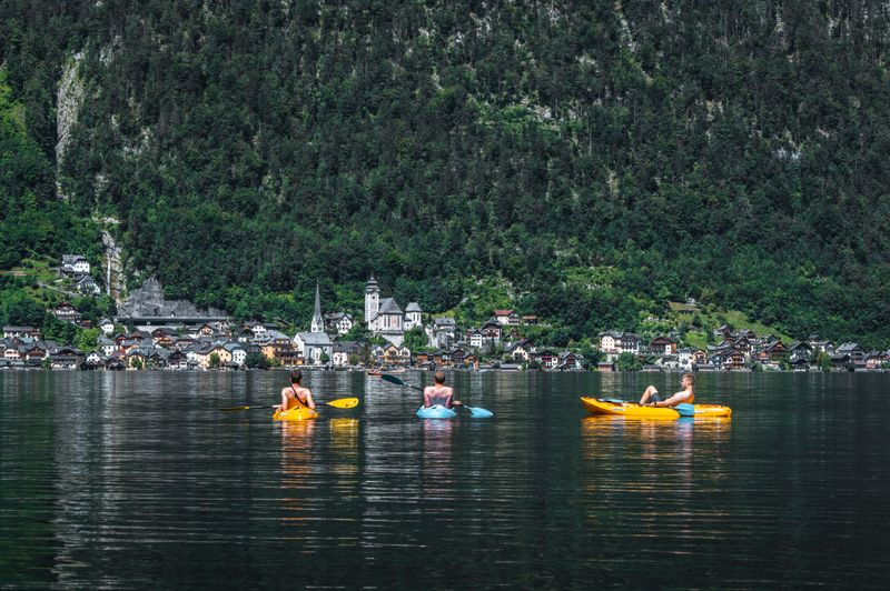 People kayaking on a calm blue lake surrounded by trees