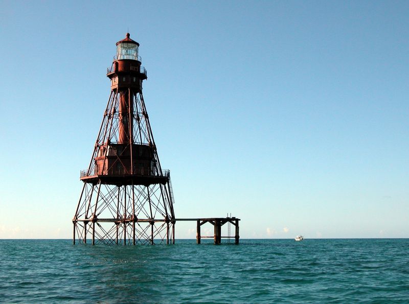 Lighthouse standing at the ocean's edge under a clear blue sky