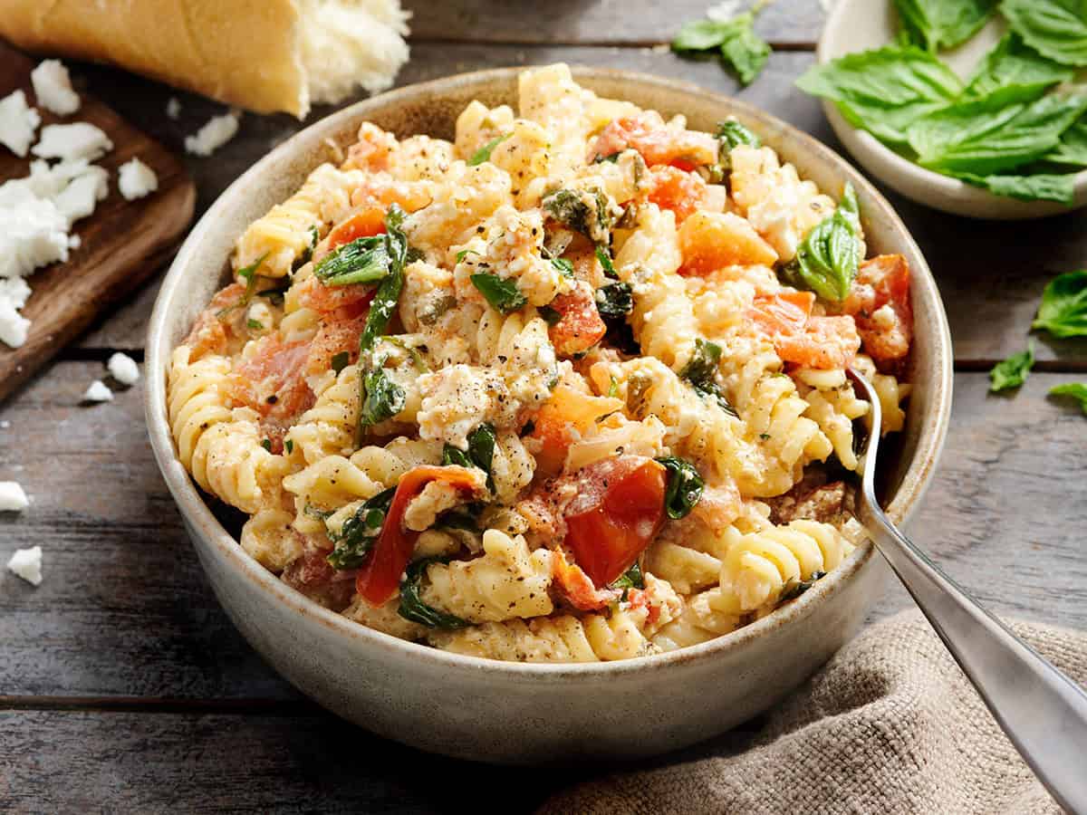 Bowl of baked feta pasta with roasted tomatoes and basil