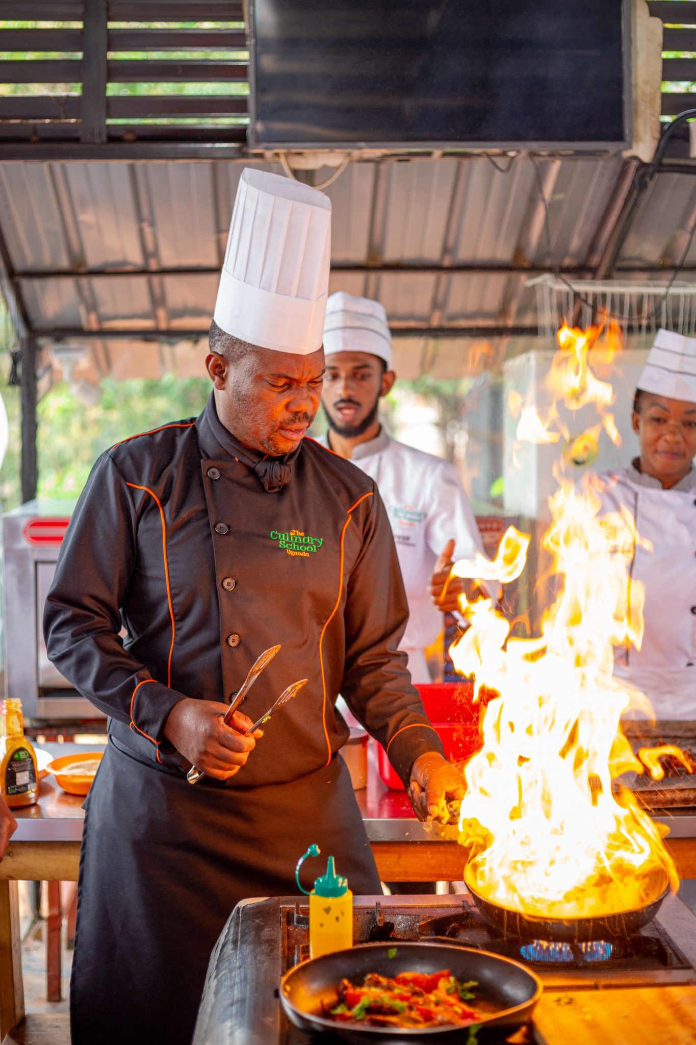 Chefs working with open flames in an outdoor kitchen