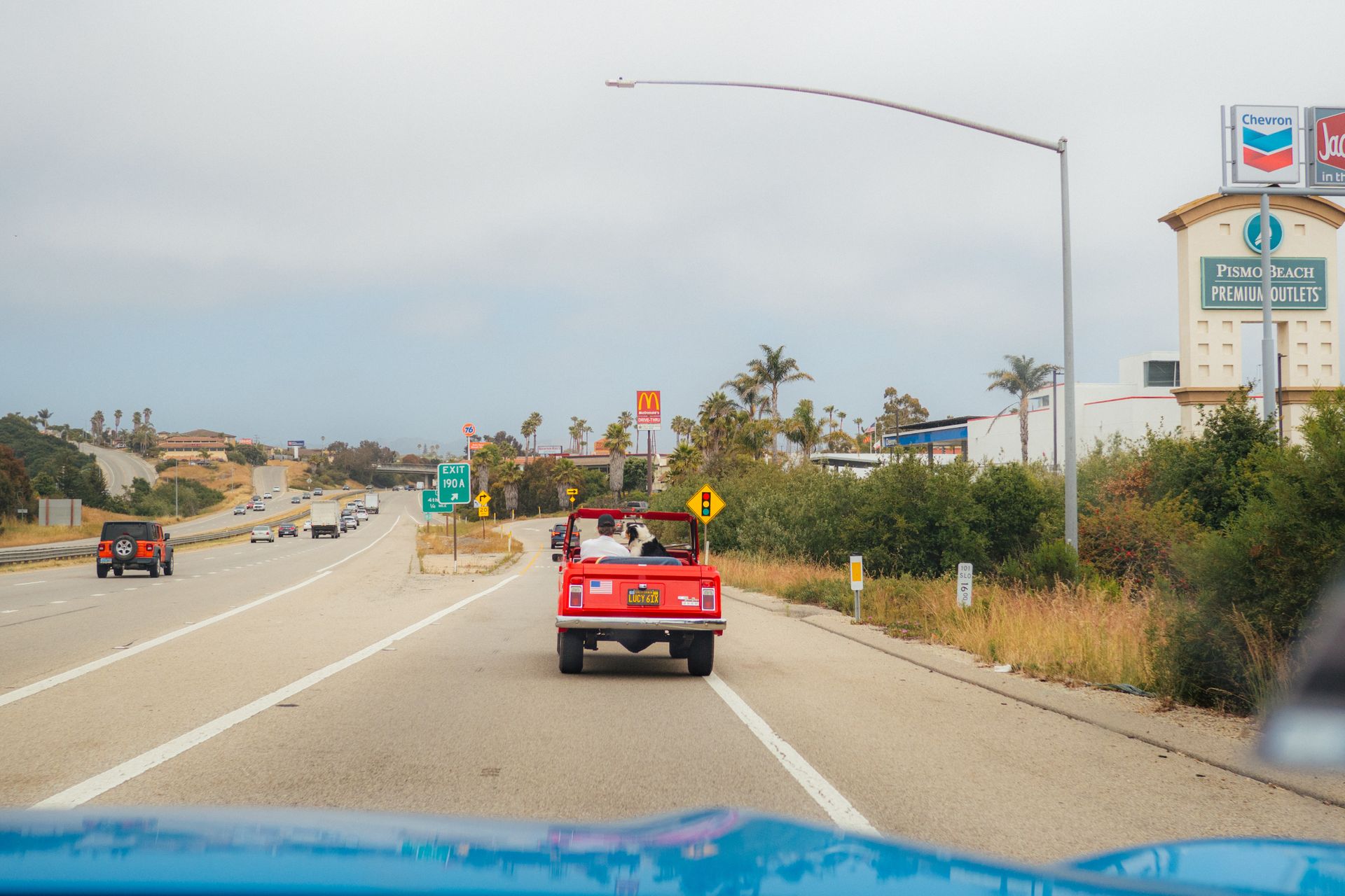 Red convertible driving along a coastal highway on a summer road trip