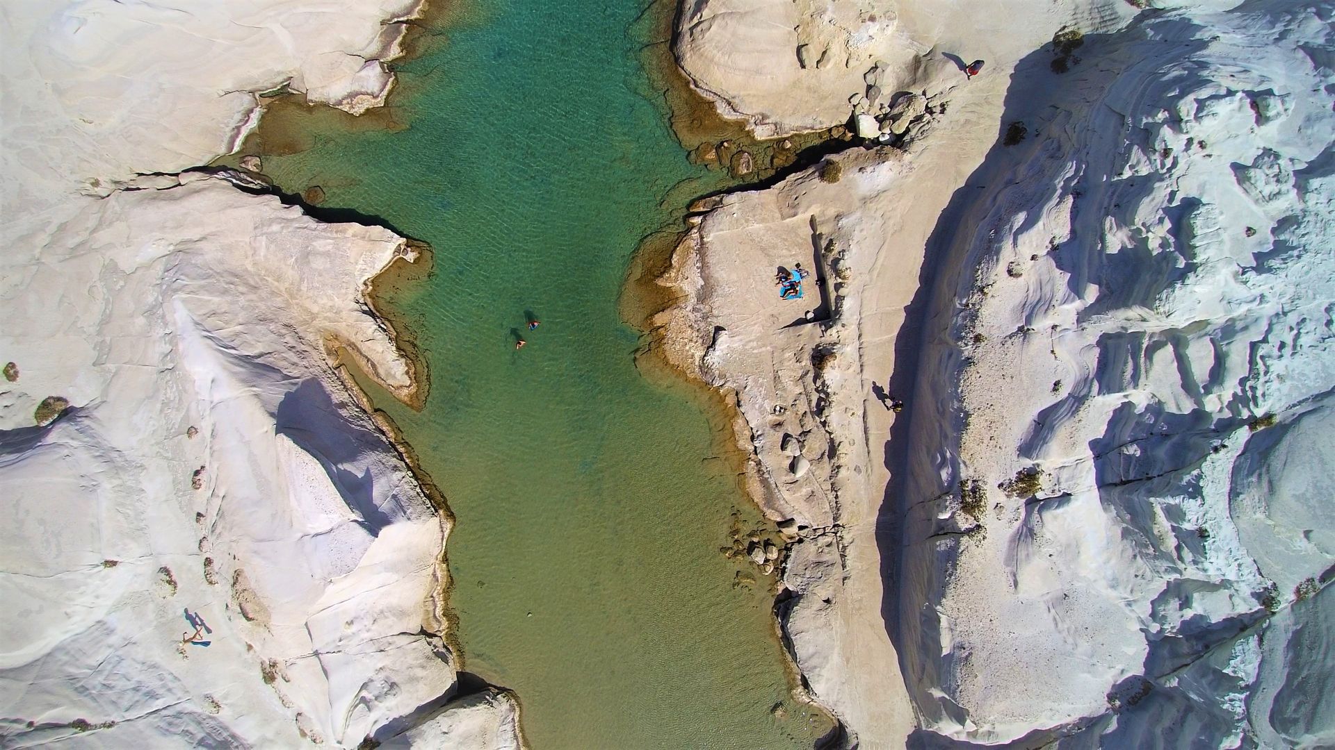 Aerial view of white volcanic rock formations and turquoise water at Sarakiniko Beach in Milos, Greece
