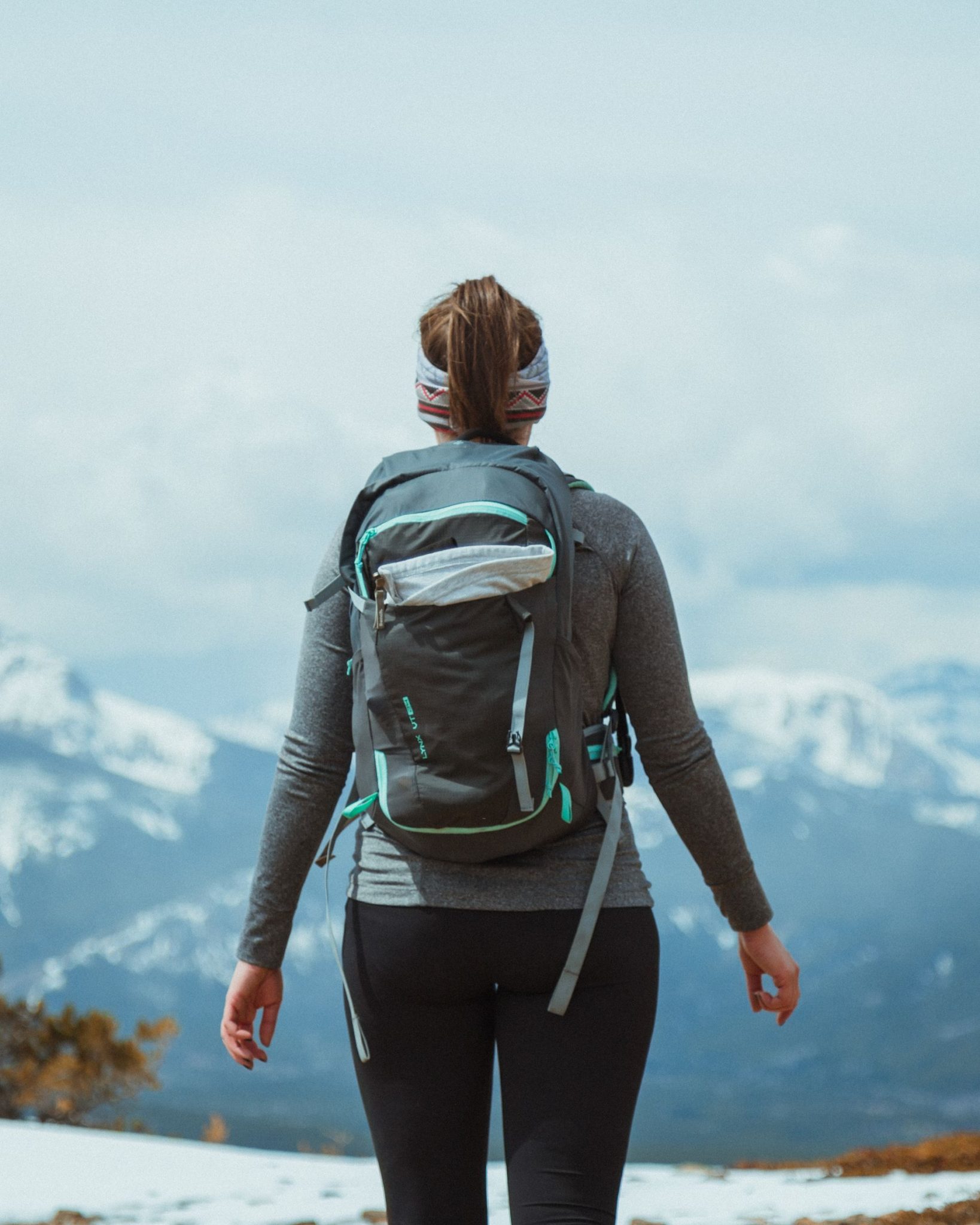 Back view of a solo female traveler with a backpack in a mountain landscape