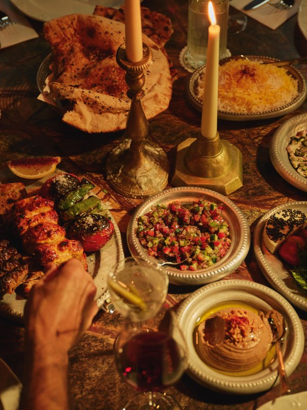 A candlelit table of Persian dishes, flatbreads, and dips at Berenjak