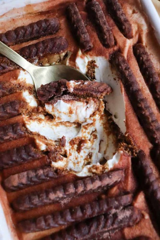 Biscoff cookies set into a dish of thick yogurt with a spoon scooping a portion