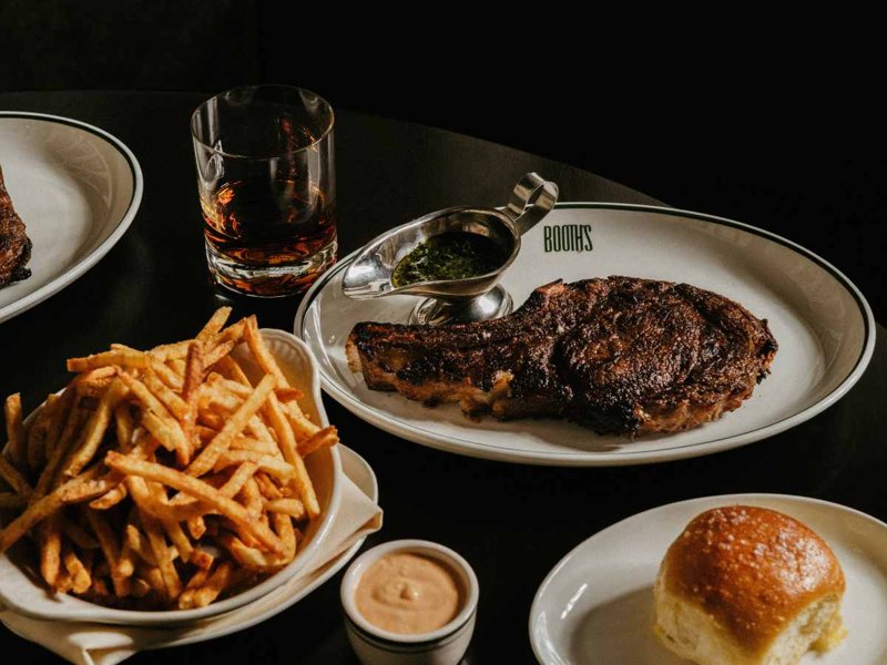 Dry-aged bone-in ribeye with fries and a cocktail at Booth's Extra Fine
