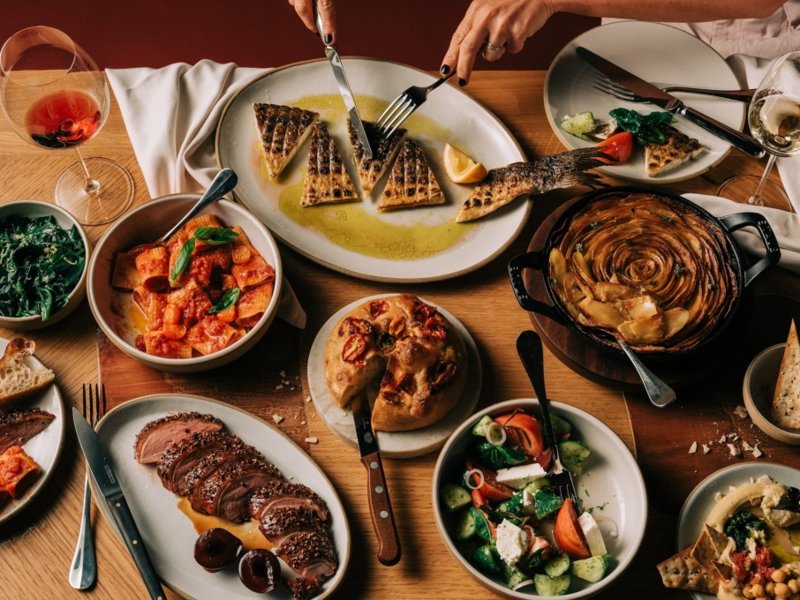 Spread of plates at Humm including grilled fish, a skillet dish, salads, and wine