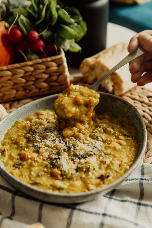 Bowl of lentil soup with a spoon and fresh vegetables